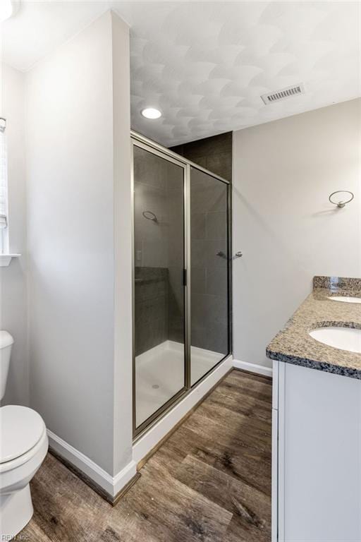 bathroom featuring an enclosed shower, vanity, wood-type flooring, and toilet