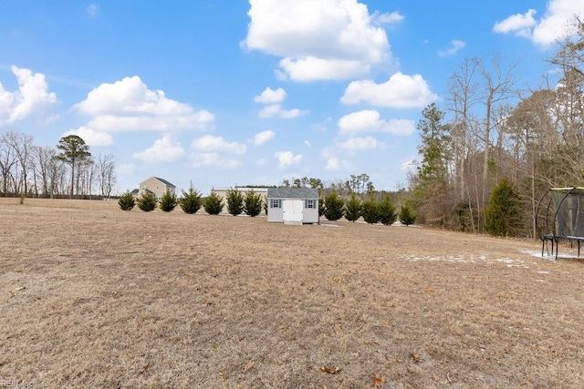 view of yard featuring a storage shed, a trampoline, and a rural view