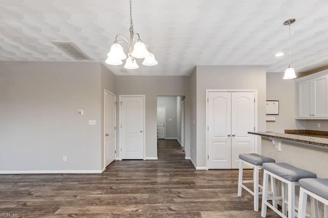 dining area featuring dark wood-type flooring and a notable chandelier