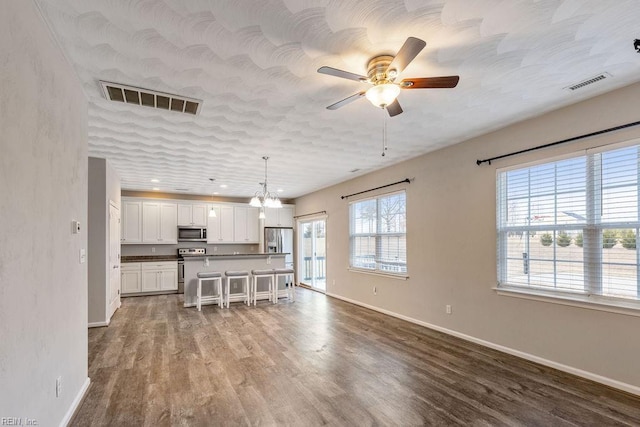 kitchen featuring hardwood / wood-style flooring, a breakfast bar area, hanging light fixtures, stainless steel appliances, and white cabinets