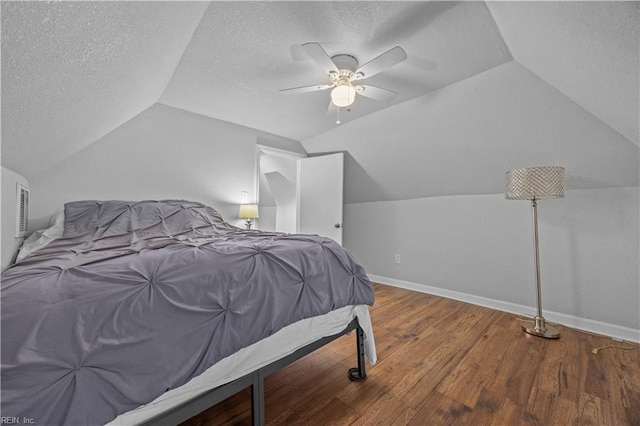 bedroom with vaulted ceiling, ceiling fan, hardwood / wood-style floors, and a textured ceiling