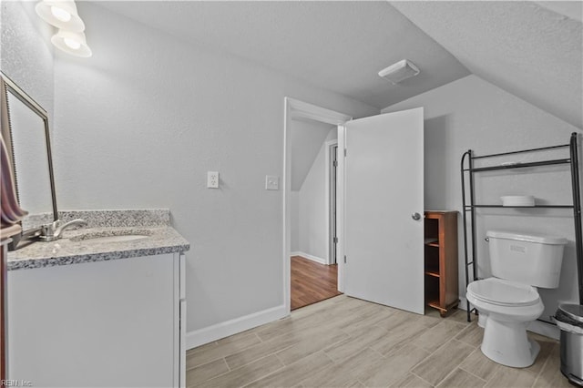 bathroom featuring lofted ceiling, vanity, toilet, and a textured ceiling