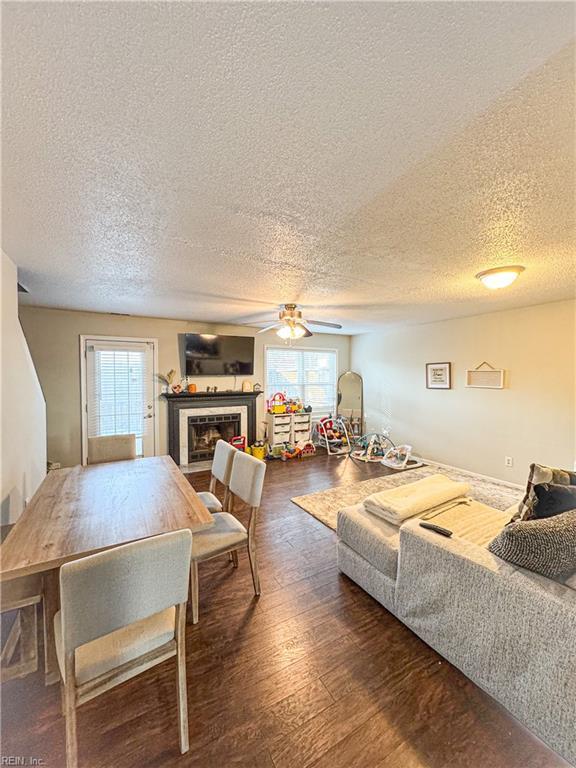 living room with ceiling fan, dark wood-type flooring, and a textured ceiling