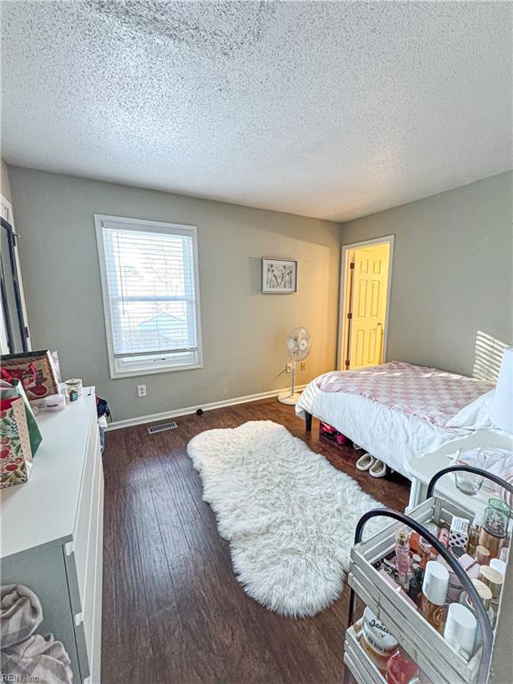 bedroom with dark hardwood / wood-style flooring and a textured ceiling