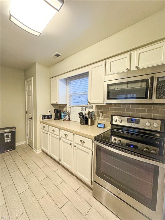 kitchen featuring stainless steel appliances and white cabinetry