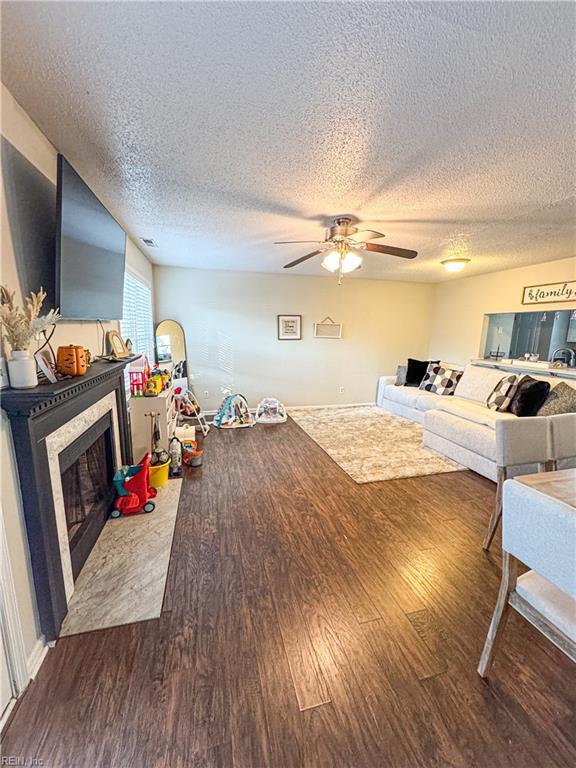 living room with wood-type flooring, a textured ceiling, and ceiling fan