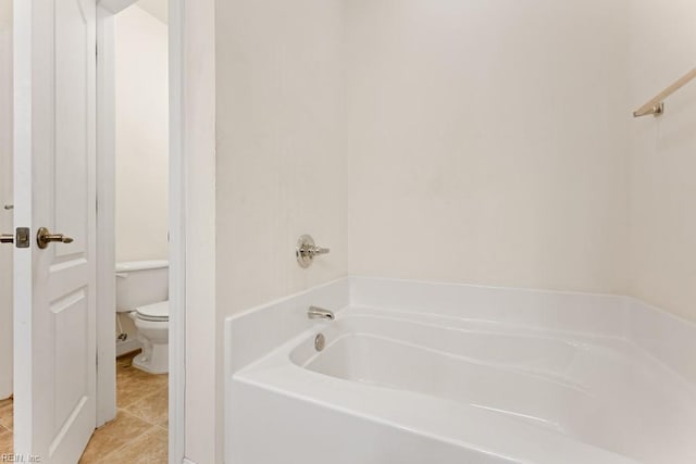 bathroom with toilet, a tub, and tile patterned flooring