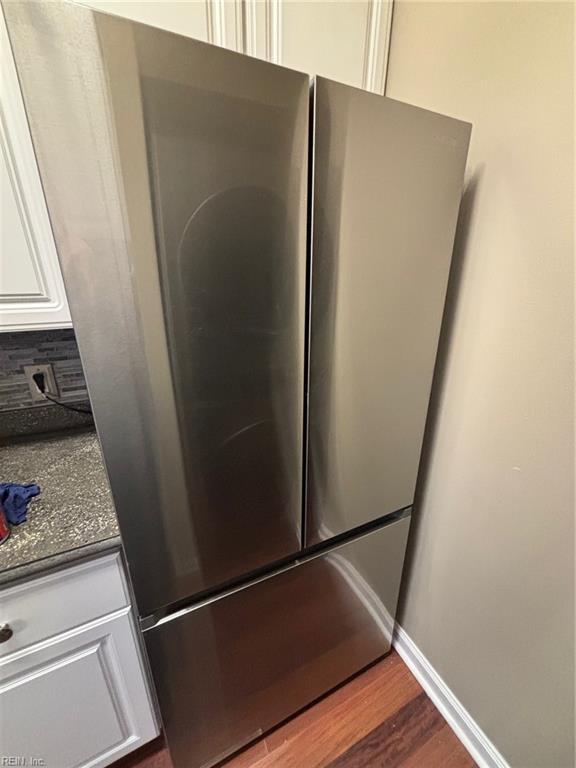 details featuring white cabinetry, stainless steel fridge, hardwood / wood-style floors, and tasteful backsplash