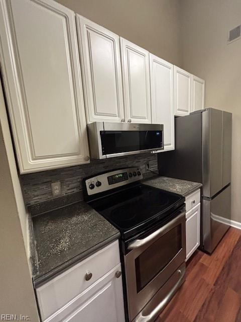 kitchen with appliances with stainless steel finishes, white cabinets, and dark hardwood / wood-style flooring