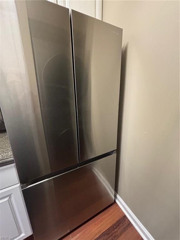 room details featuring white cabinets, stainless steel fridge, and wood-type flooring