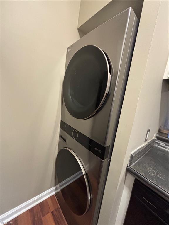 washroom with stacked washing maching and dryer and dark hardwood / wood-style floors