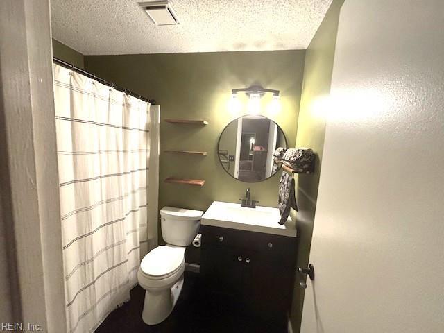 bathroom with vanity, toilet, and a textured ceiling