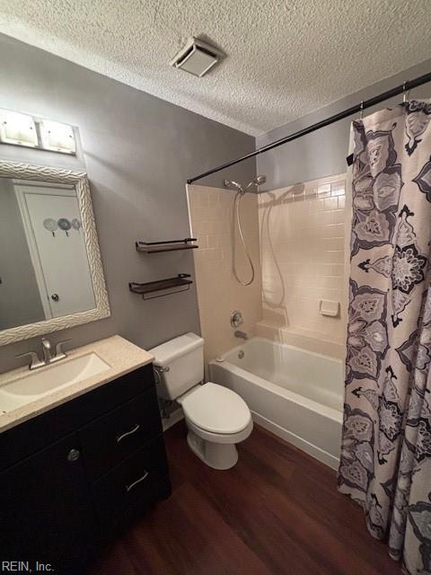 full bathroom with toilet, a textured ceiling, vanity, shower / bathtub combination with curtain, and hardwood / wood-style floors