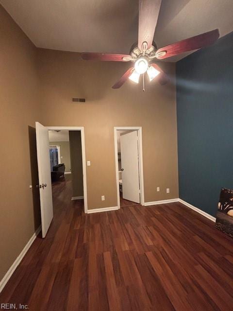 unfurnished bedroom featuring a towering ceiling, dark hardwood / wood-style floors, and ceiling fan