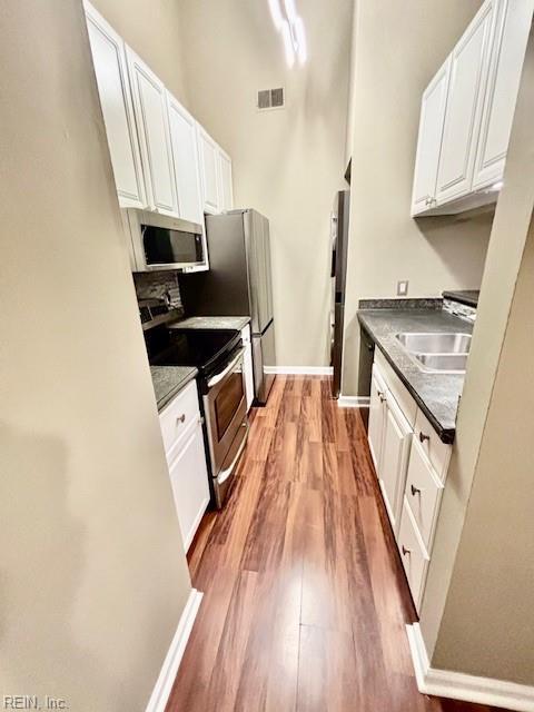 kitchen featuring white cabinetry, appliances with stainless steel finishes, sink, and light wood-type flooring