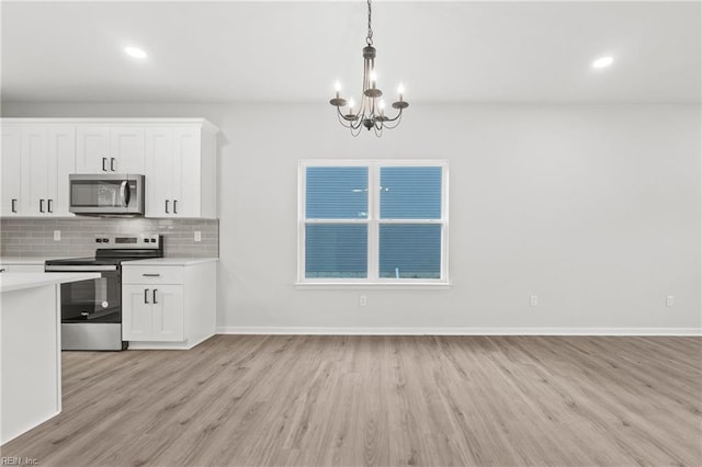 kitchen with white cabinetry, appliances with stainless steel finishes, decorative backsplash, and pendant lighting