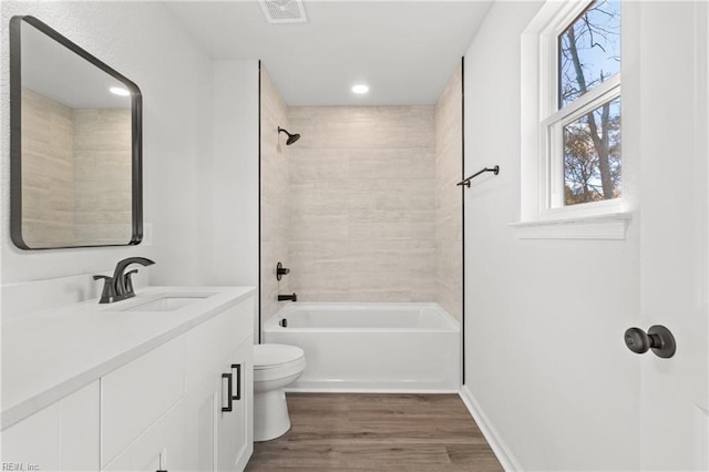 full bathroom featuring vanity, toilet, tiled shower / bath combo, and hardwood / wood-style floors