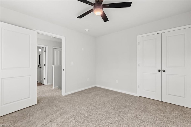 unfurnished bedroom with light colored carpet, a closet, and ceiling fan