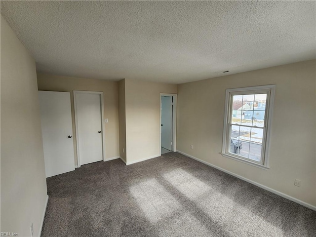 unfurnished bedroom featuring a textured ceiling and dark carpet