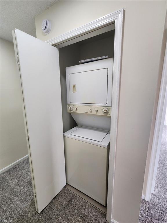 washroom with dark colored carpet and stacked washing maching and dryer