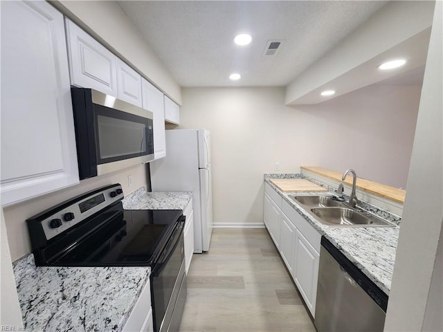 kitchen featuring stainless steel appliances, light hardwood / wood-style floors, sink, and white cabinets