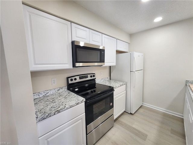 kitchen with white cabinetry, range with electric stovetop, light hardwood / wood-style floors, and white fridge