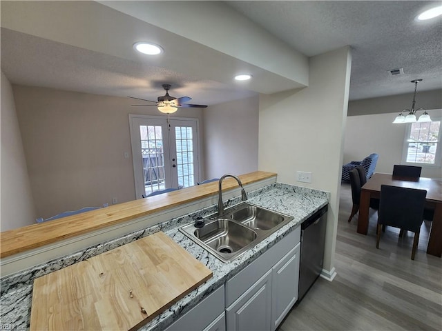 kitchen featuring pendant lighting, dishwasher, wood-type flooring, sink, and a textured ceiling