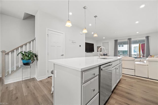 kitchen featuring sink, dishwasher, a kitchen island with sink, light hardwood / wood-style floors, and decorative light fixtures