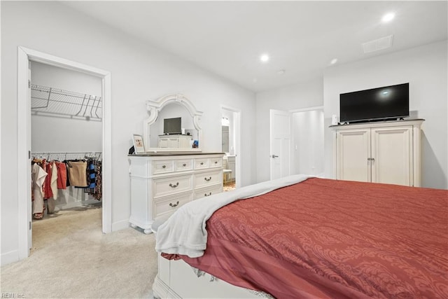 bedroom featuring light carpet, a spacious closet, and a closet