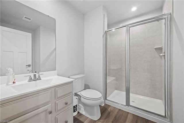 bathroom with hardwood / wood-style flooring, vanity, toilet, and a shower with shower door