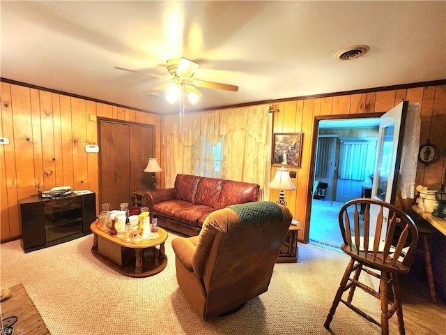 living room with ceiling fan, light colored carpet, and wood walls