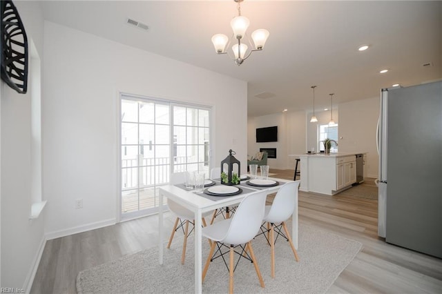 dining area featuring an inviting chandelier, a healthy amount of sunlight, and light hardwood / wood-style flooring