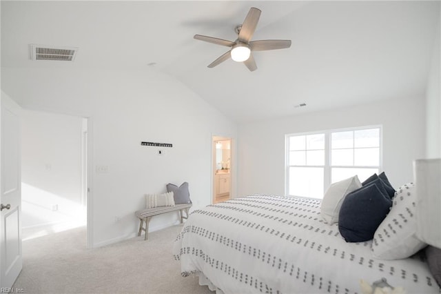 carpeted bedroom featuring ceiling fan, vaulted ceiling, and ensuite bath