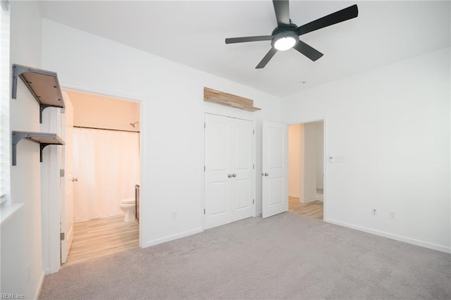 unfurnished bedroom with light colored carpet, a closet, ceiling fan, and ensuite bathroom