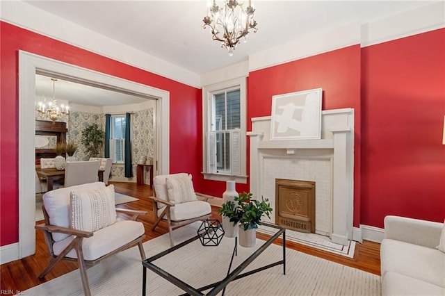 sitting room with hardwood / wood-style flooring, a notable chandelier, and a fireplace