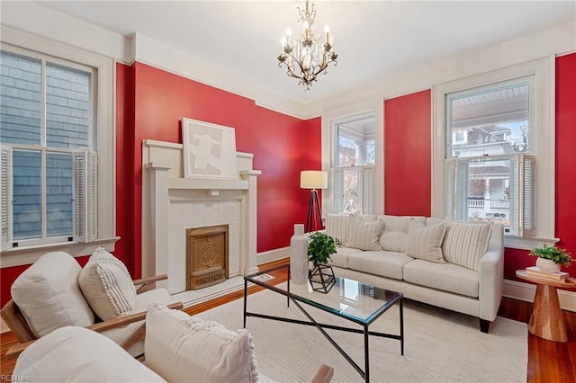 living room featuring a brick fireplace, plenty of natural light, a chandelier, and light wood-type flooring