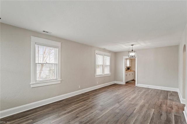 spare room featuring a notable chandelier and wood-type flooring