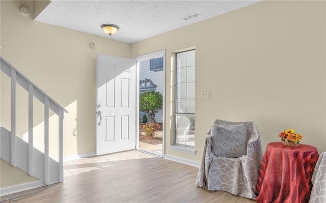 foyer entrance featuring a textured ceiling and light wood-type flooring