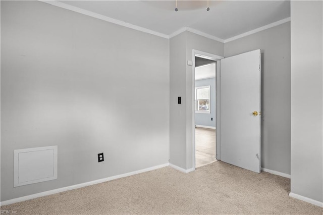 empty room with ornamental molding and light colored carpet