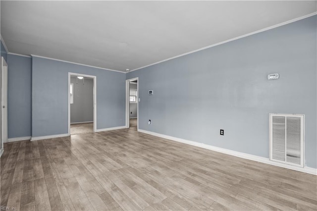 empty room featuring crown molding and light wood-type flooring