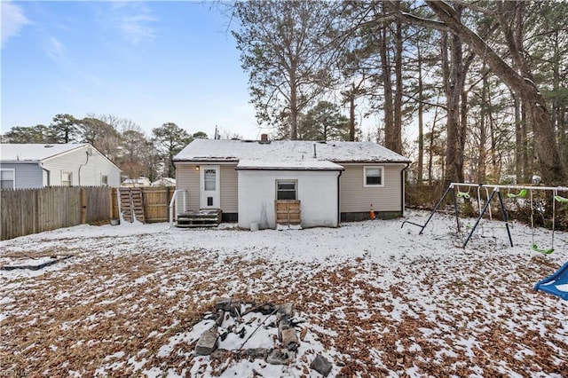 snow covered rear of property with a playground