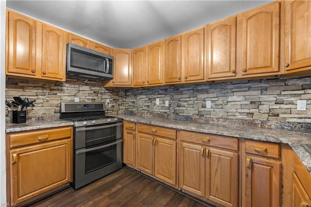 kitchen featuring stainless steel appliances, dark stone countertops, dark hardwood / wood-style flooring, and decorative backsplash