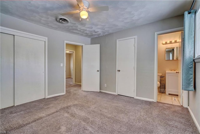 unfurnished bedroom with ensuite bathroom, light carpet, ceiling fan, and a closet