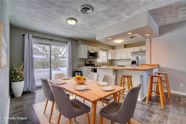 dining room with sink, dark hardwood / wood-style floors, and a textured ceiling