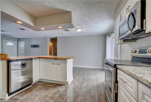 kitchen featuring hardwood / wood-style floors, stainless steel appliances, kitchen peninsula, and white cabinets