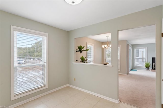 spare room with a chandelier and light carpet