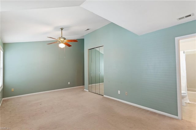 empty room featuring vaulted ceiling, light colored carpet, and ceiling fan