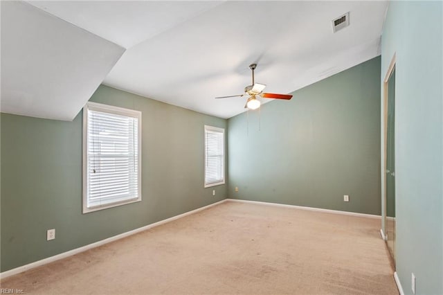 empty room featuring lofted ceiling, light carpet, and ceiling fan