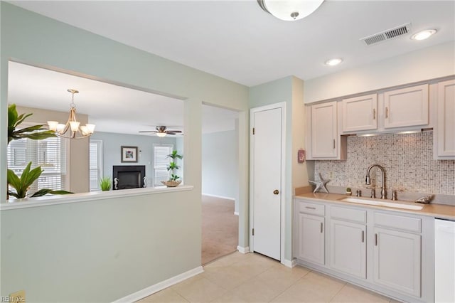 kitchen with pendant lighting, white cabinetry, sink, backsplash, and white dishwasher