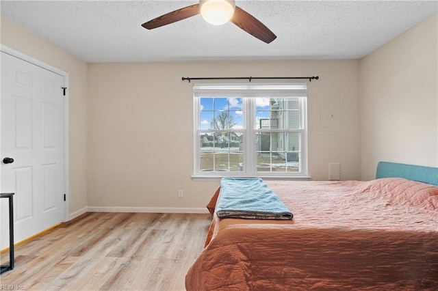 bedroom featuring ceiling fan, a textured ceiling, and light wood-type flooring